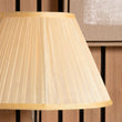 Close-up of a pleated almond silk  lampshade against a wooden background