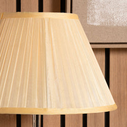 Close-up of a pleated almond silk  lampshade against a wooden background