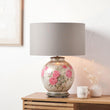 Decorative table lamp with floral design on a wooden surface.