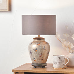 Decorative Jenny Worrall JW72 table lamp with a floral design on a wooden surface next to a mug and decorative items.